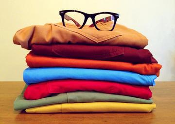Different colored folded with glasses on top.